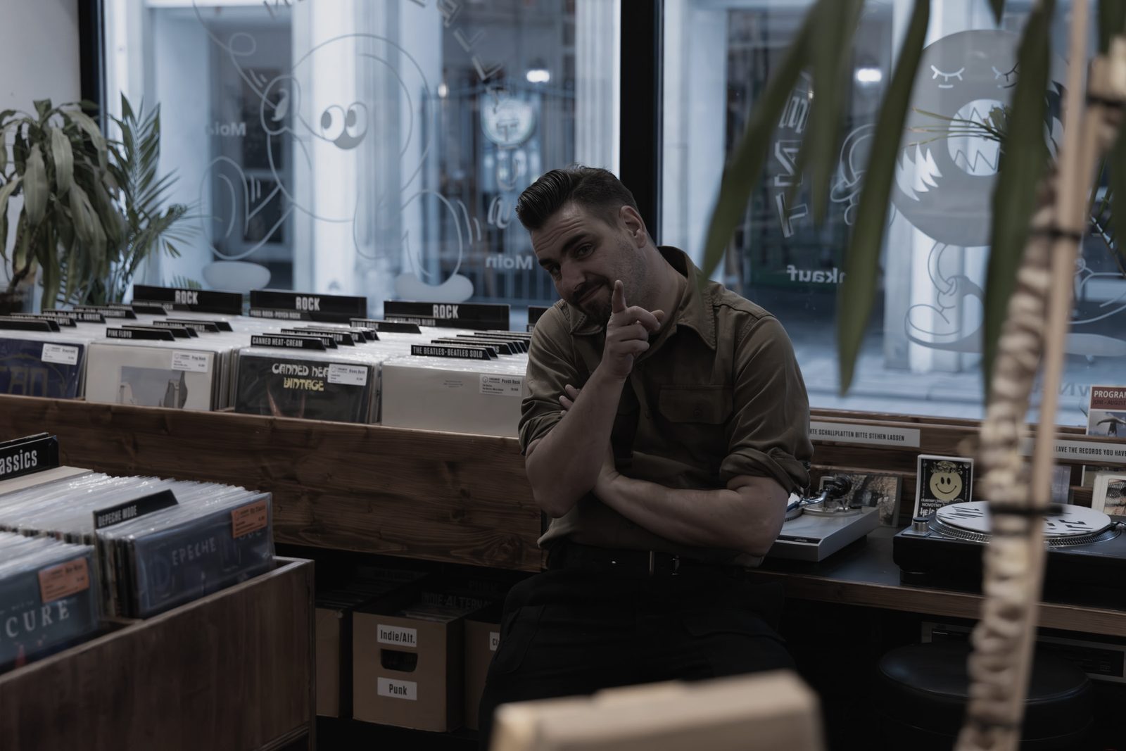 Mario Schoo im Laden, dahinter das Schaufenster mit der beschrifteten Scheibe.