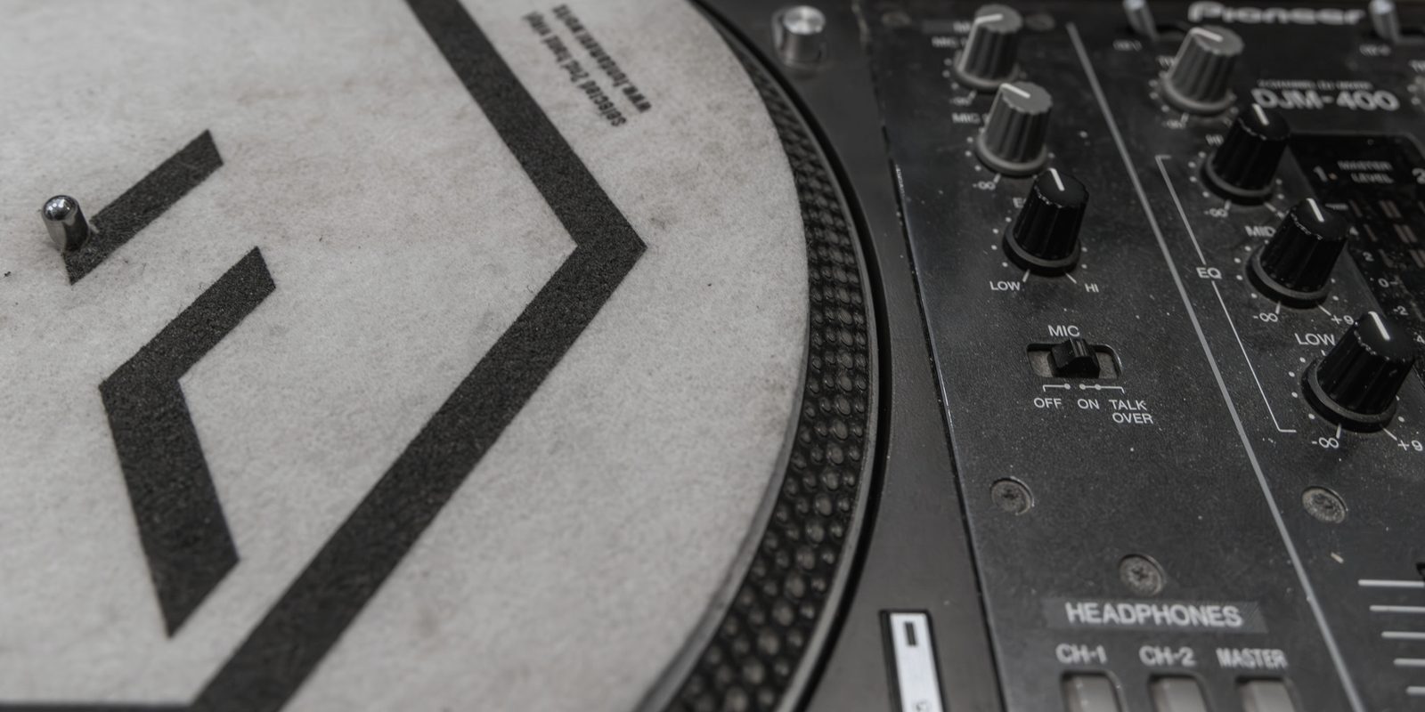 Plattenteller mit FUNDAMENT-Slipmat, daneben ein DJ-Mischpult.